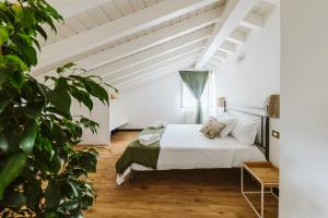 a white bedroom with a bed and a plant at Casa Rucola in Sestri Levante