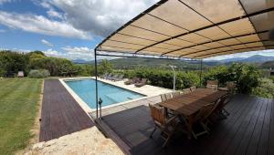 a wooden deck with a table and a swimming pool at Ermitage Crestet (Ventoux - Provence) in Crestet
