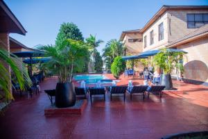 eine Terrasse mit Stühlen und einem Tisch sowie ein Pool in der Unterkunft Mika Hotel Kabulonga in Lusaka