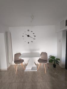 a white table with two chairs and a clock on the wall at Apartament Bianco in Brăila