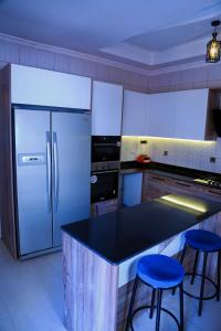 a kitchen with a refrigerator and two blue bar stools at KiGALI COMFORT AND CLASSIC STAY APARTMENT in Kigali