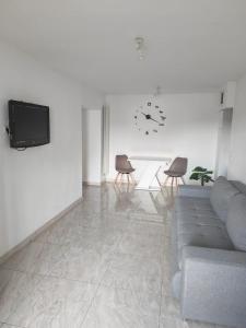 a living room with a couch and two chairs and a clock at Apartament Bianco in Brăila