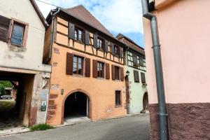 an old building with an archway next to a street at voyage en Alsace chez Gaby in Hunawihr