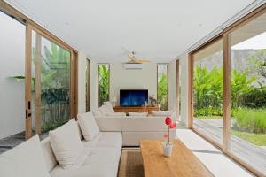 a living room with white furniture and large windows at Casa de Rua Villas in Badung