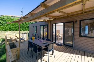a wooden deck with a table and chairs on it at Camping La Grappe Fleurie in Fleurie