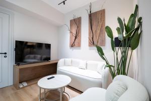 a living room with a white couch and a tv at Saturn ApartHotel Tirana in Tirana