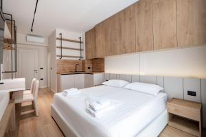 a bedroom with a large white bed and a desk at Saturn ApartHotel Tirana in Tirana