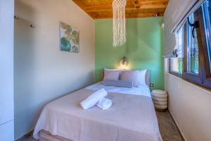 a small bedroom with a white bed with towels on it at Olive & Wave Cottage in Karousádes +43 photos
