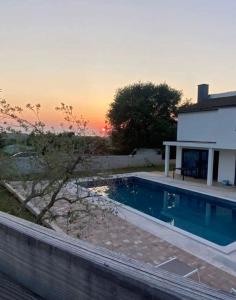 a swimming pool in front of a house with a sunset at Villa Klara in Gedići