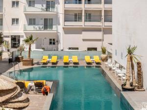 a swimming pool with yellow lounge chairs and a building at 4BR Newly Renovated Retreat Tranquil Coastal Haven in Hersonissos