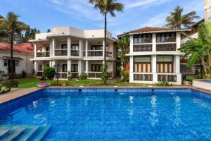 a villa with a swimming pool in front of a house at Resort Coqueiral - A Portuguese Heritage Stay by the Sea in Candolim