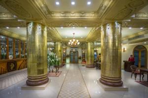 een lobby van een gebouw met zuilen en een kroonluchter bij Luxus Grand Hotel in Lahore