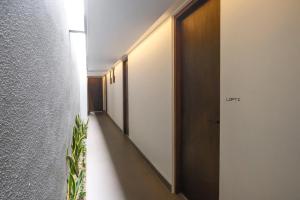 a hallway with white walls and a hallway with a plant at Sunset Loft Seminyak, Bali in Seminyak