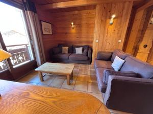 a living room with couches and a table in a cabin at Appartement Chez Marion in Notre-Dame-de-Bellecombe