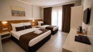 a hotel room with two beds and a television at Palm Beach Hotel in Silifke