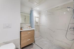 a white bathroom with a shower and a sink at Résidence Pierre et Vacances Cap Cassis Calanques in Roquefort-la-Bédoule