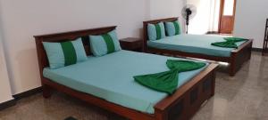 two beds in a room with green sheets at Velora Resort in Anuradhapura