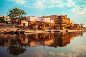 a group of buildings next to a river with boats at Vivanta Vrindavan in Vrindāvan