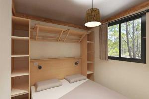 a bedroom with a bed with shelves and a window at Chalet Cannelle Spa camping Buffalo Hacienda in La Seyne-sur-Mer