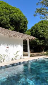 a swimming pool in front of a building with a thatch roof at Maison le Rêve in Nosy Be
