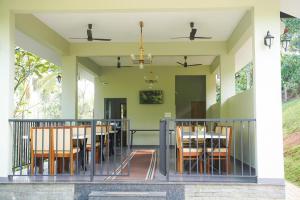 a dining room with a table and chairs on a balcony at Skyleaf Resort in Meenangadi