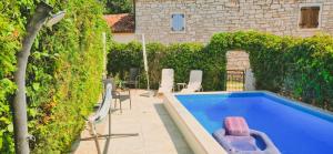 a swimming pool with a pink chair in a yard at Istria Stone House in Marasi +26 photos