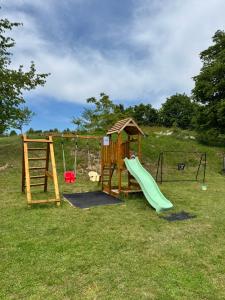 a playground with a slide and a swing at Guest House Aurora in Poljanak