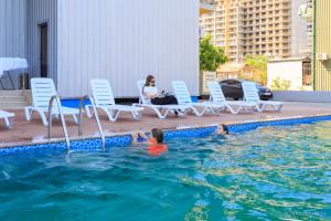 two children in a swimming pool with a woman sitting on chairs at Hotel Scorpio gonio in Gonio