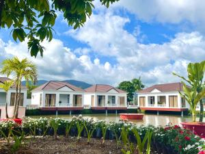 a row of houses with flowers and palm trees at Rồng Vàng Resort in Tri Tôn
