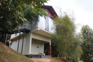 a white house with a balcony and trees at Skyleaf Resort in Meenangadi