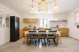 a kitchen with a table with chairs and a black refrigerator at Seafront Villa in Kornati Private Terrace and Direct Beach Access in Kornati