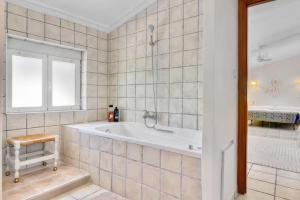 a white bathroom with a tub and a window at Dhara Wellness Villa in Benirrama