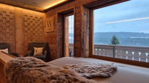 a bedroom with a bed and a large window at Chalet Auszeit - Wohlfühlzeit Naturdesign Chalet`s in Rimbach
