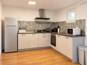 a kitchen with a white refrigerator and a microwave at Piscine et pétanque - Calme proche Belfort in Châlonvillars