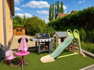 a backyard with a playground with a slide and a grill at Piscine et pétanque - Calme proche Belfort in Châlonvillars