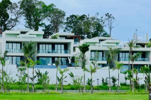 a white building with palm trees in front of it at Xanadu International Resort in Koh Rong Sanloem