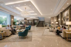 a lobby with people sitting on couches and chairs at Hotel Park Green Suites Delhi Airport in New Delhi