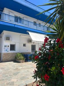 a white building with a white awning and red flowers at House Stamatis in Sarti
