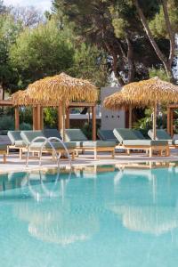 a swimming pool with lounge chairs and a straw umbrella at Aubamar Palma Resort in Playa de Palma
