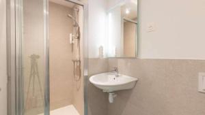 a bathroom with a sink and a shower with a mirror at Kyriad ECO - Dijon Sud Chenove in Chenôve