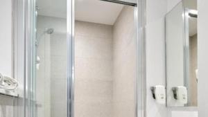 a shower with a glass door in a bathroom at Kyriad ECO - Dijon Sud Chenove in Chenôve +40 photos