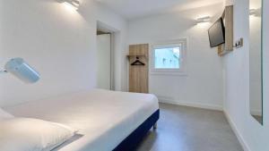 a white bedroom with a bed and a window at Kyriad ECO - Dijon Sud Chenove in Chenôve