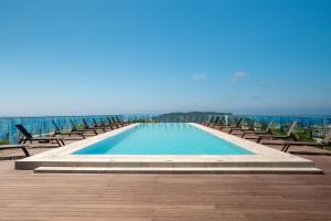 a swimming pool with chairs and the ocean in the background at Sobre Suites in Bečići