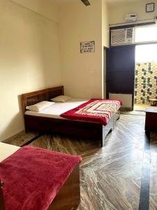 a bedroom with two beds and a red blanket at Shri Ved Vrinda Dham Aashram in Chhatikara +23 photos