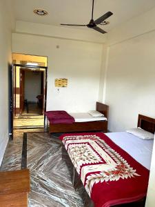 a bedroom with two beds and a ceiling fan at Shri Ved Vrinda Dham Aashram in Chhatikara