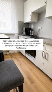 Eine Küche mit weißen Schränken und Holzboden in der Unterkunft NOVA Living, Balkon, Nähe Altstadt & kostenlose Tiefgarage in Würzburg