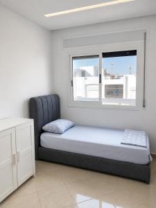 a bed sitting in a room with a window at Appartement MIRAMAR in Martil