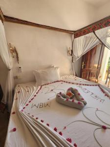 a bed with red rose petals on it at Wow Beach House in Jambiani