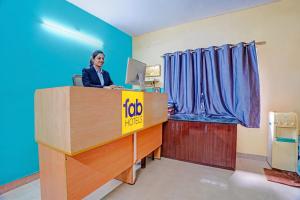 a woman sitting at a desk with a laptop at FabHotel Nimalan Residency Tambaram in Chennai