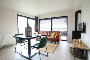 a living room with a couch and a table and chairs at Cube la Mer 4 in Olburgen